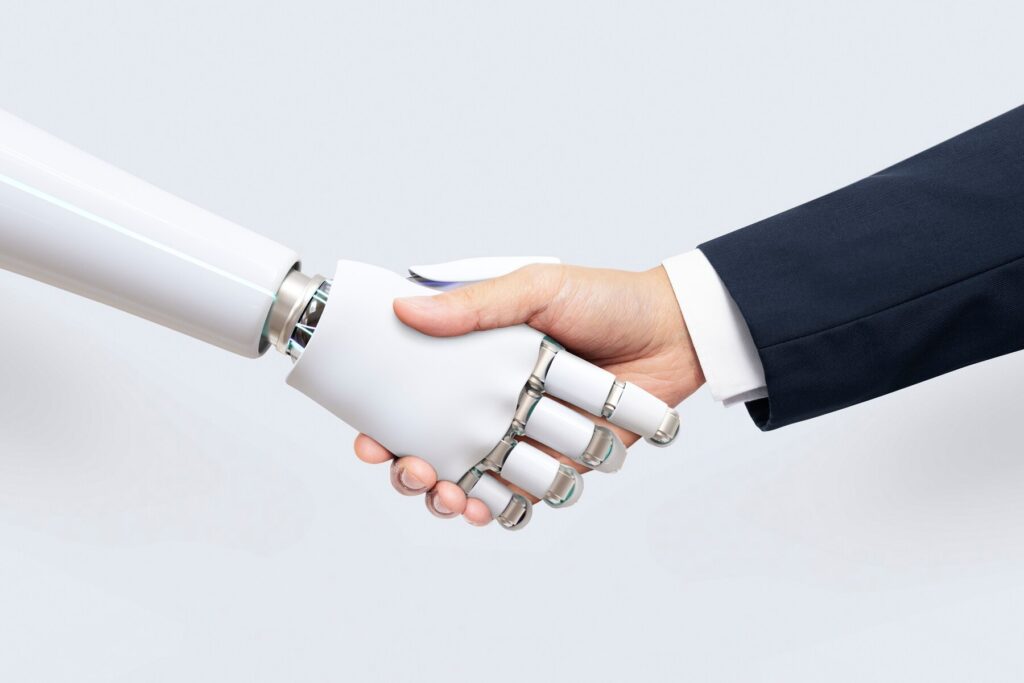 A human hand shakes a sleek, white robotic hand, symbolizing collaboration between technology and humanity.