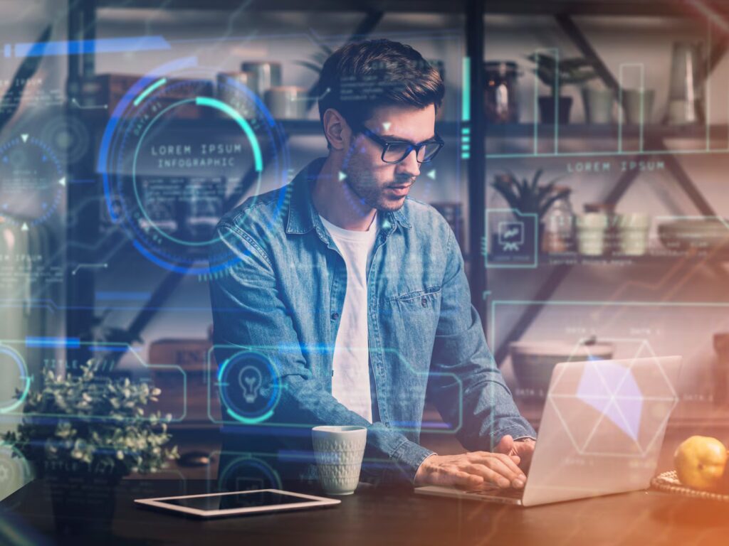 A person in a denim jacket works on a laptop at a desk, surrounded by digital graphics and modern home decor.