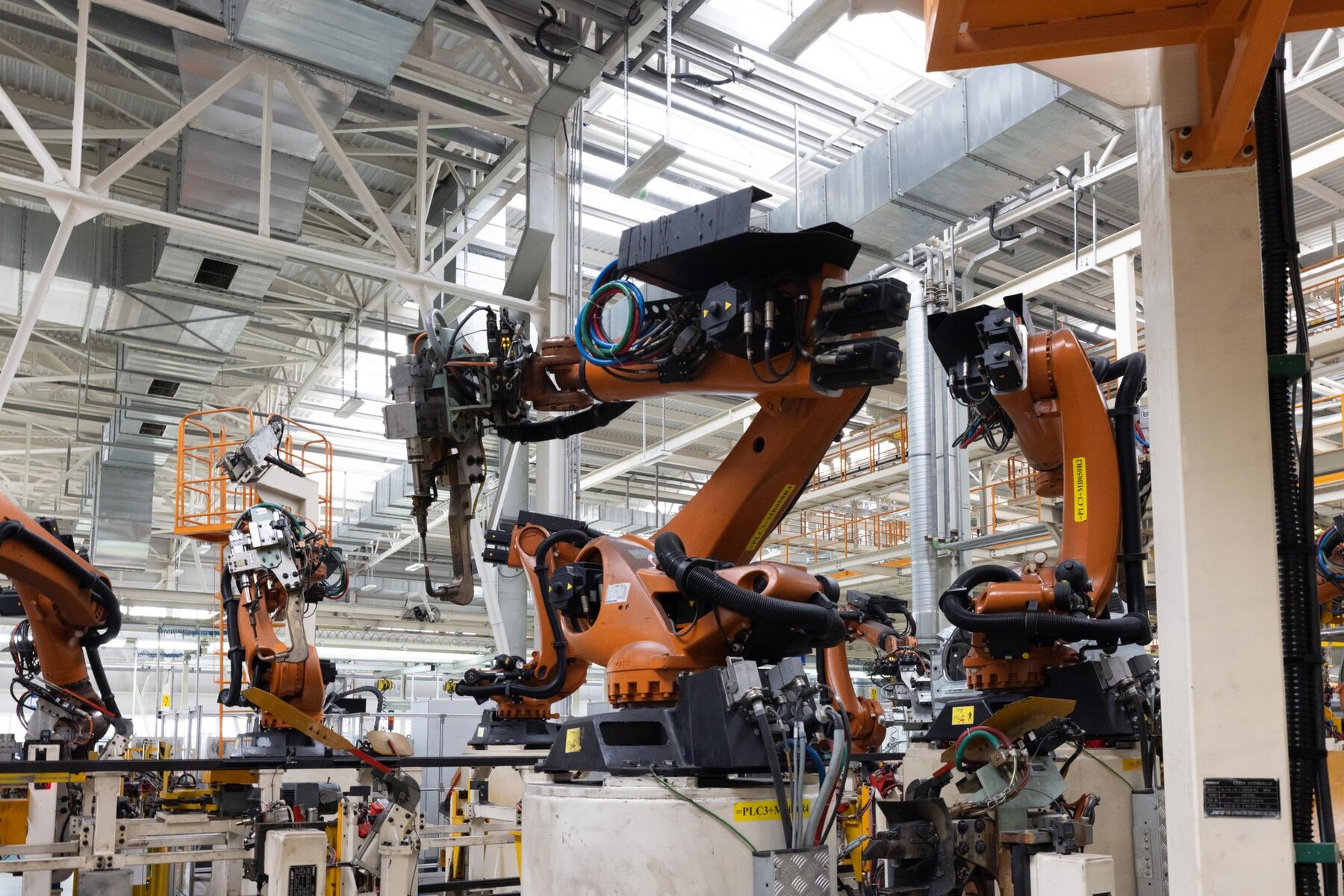 A factory scene featuring several robotic arms with intricate machinery, showcasing an advanced automation setup in production.