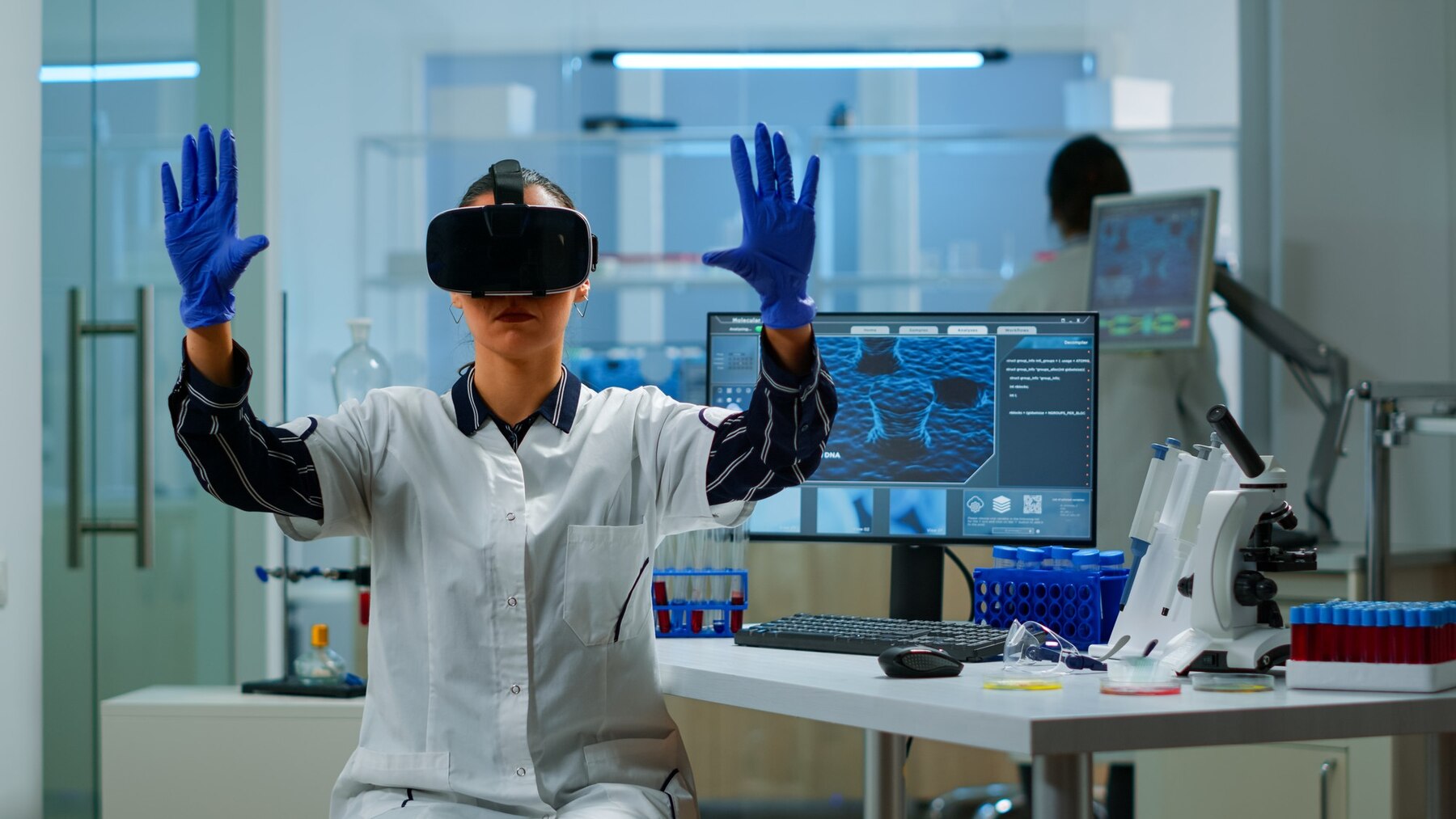 A lab technician wearing gloves and a lab coat engages with virtual reality technology in a modern laboratory setting, surrounded by scientific equipment.