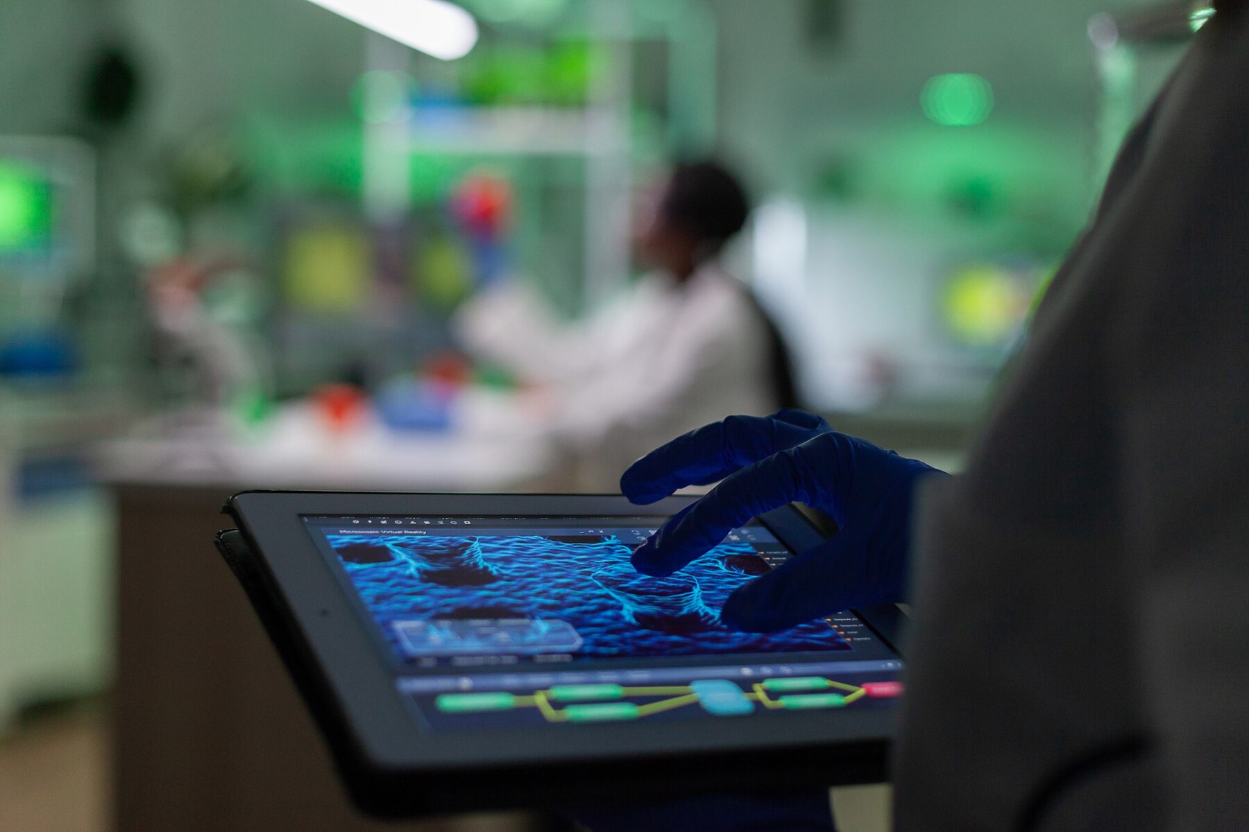 A researcher in a lab uses a tablet displaying microscopic data, with colorful lab equipment in the background.