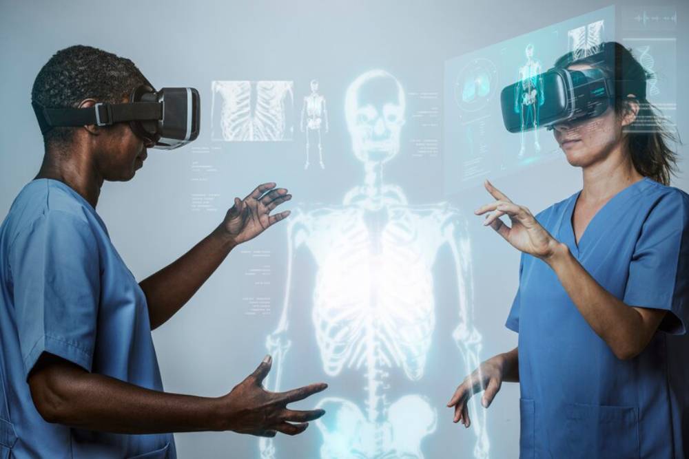 Two medical professionals in scrubs use virtual reality headsets, interacting with a holographic human skeleton display.