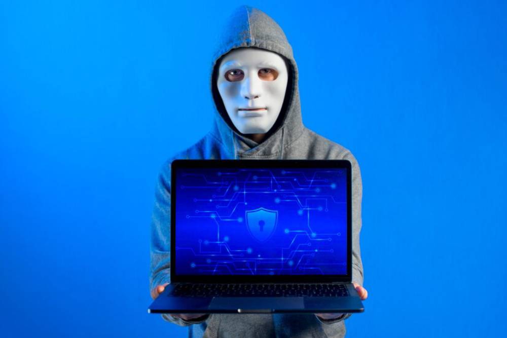 A person holds a laptop displaying a blue background with a shield and circuit patterns, symbolizing srcurity.